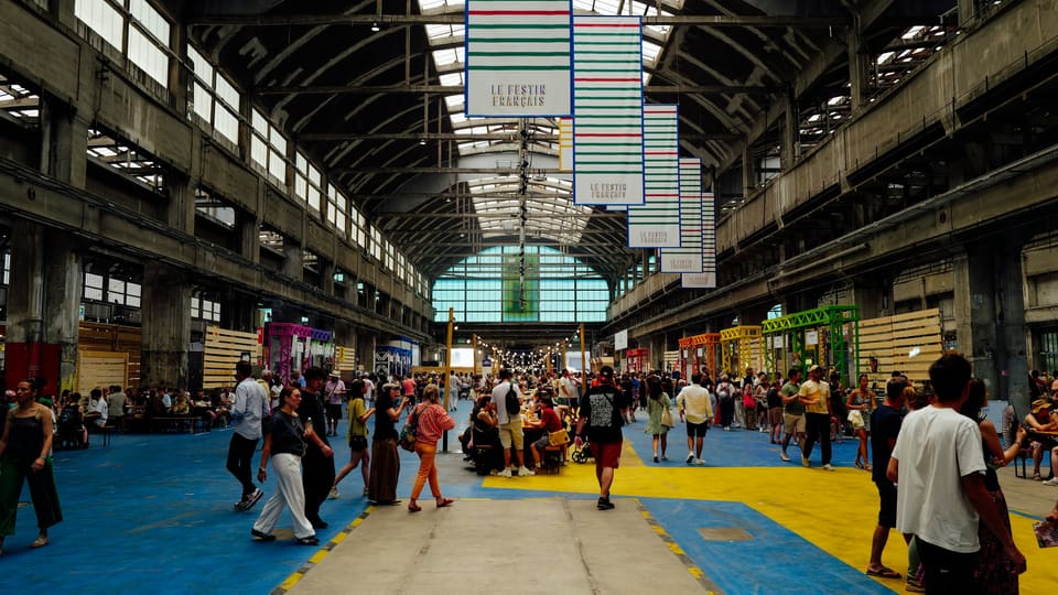 People walking through a large, busy indoor hall